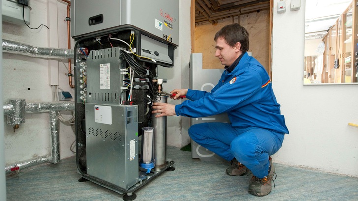 Ein Installateur installiert ein BHKW mit Brennstoffzellen. - © Callux
